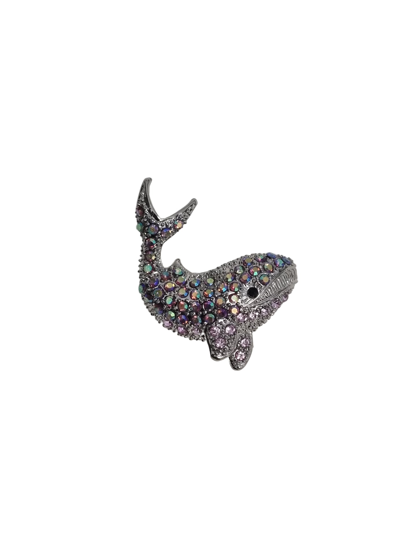 Shiny whale-shaped brooch on a white fabric background